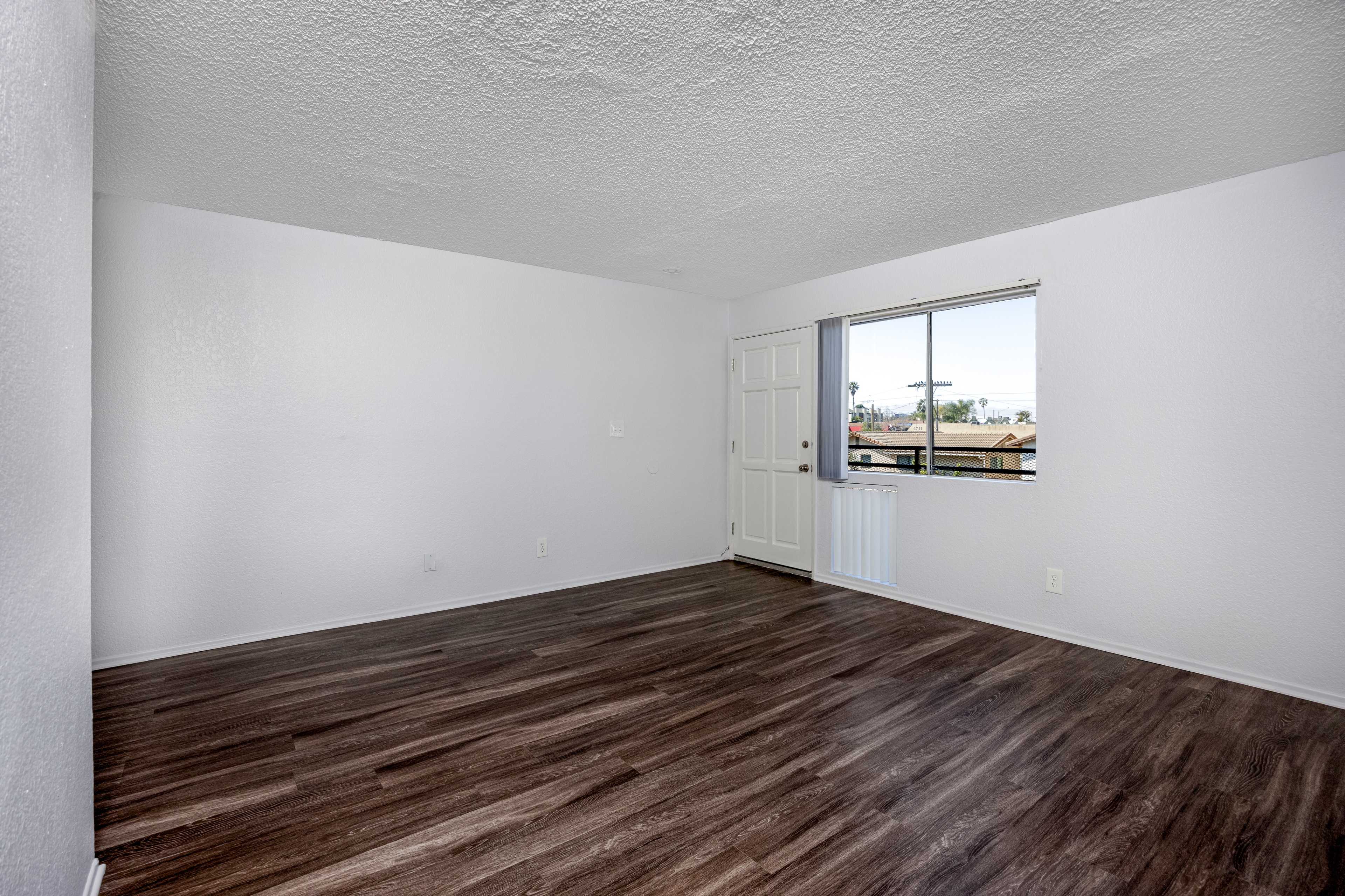 Empty room with wooden flooring and a window.
